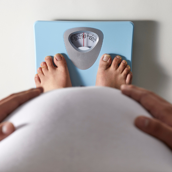 Mujer embarazada pesándose en una balanza